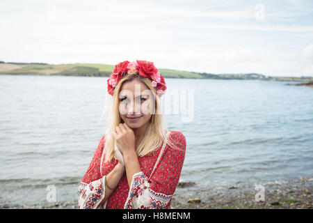 Donna bionda che indossa un fiore tiara in piedi vicino a un fiume Foto Stock