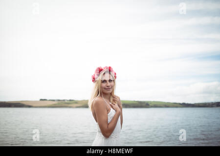 Donna bionda che indossa un fiore tiara in piedi vicino a un fiume Foto Stock