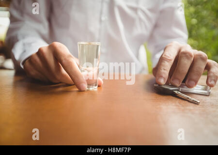 Uomo con un bicchiere di tequila shot e chiave auto nel bancone bar Foto Stock