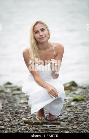 Carefree donna bionda accovacciati vicino a un fiume Foto Stock