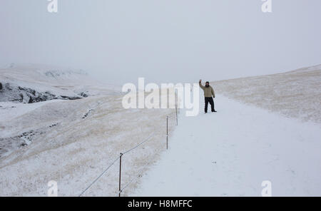 Un uomo cammina su un sentiero innevato accanto al Canyon Fjaðrárgljúfur nel sud-est dell'Islanda Foto Stock