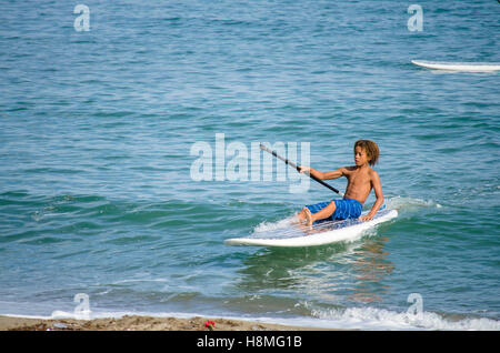 Ragazzo giovane paddle boarding, Paddleboarding, nel mare mediterraneo, Spagna. Foto Stock