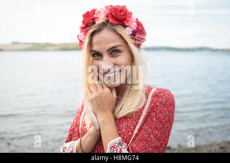 Donna bionda che indossa un fiore tiara in piedi vicino a un fiume Foto Stock