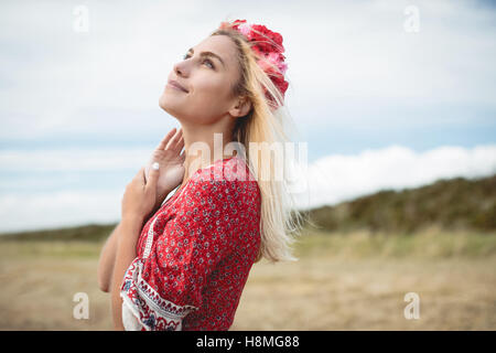 Donna bionda che indossa un fiore tiara in piedi in campo Foto Stock