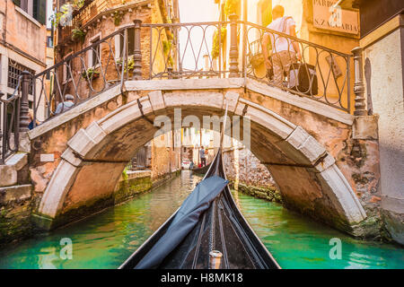 Tradizionali gondole su stretto canale in beautiful Golden luce della sera al tramonto in estate a Venezia, Italia Foto Stock