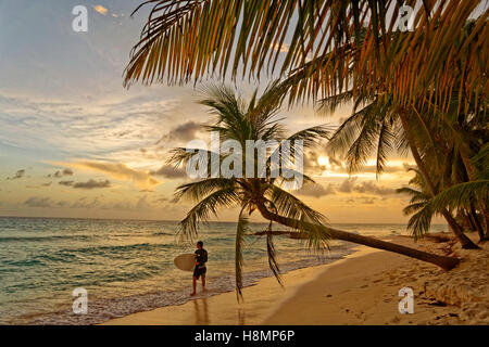 Surfer e tramonto a Dover Beach, St. Lawrence Gap, costa sud di Barbados, dei Caraibi. Foto Stock