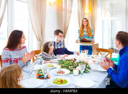 Happy amici seduti attorno a un tavolo e godersi la cena di Natale insieme Foto Stock