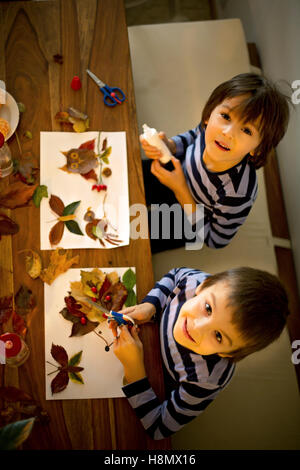 Dolce bambino, ragazzo, applicando le foglie utilizzando colla pur facendo arti e mestieri a scuola, autumntime Foto Stock