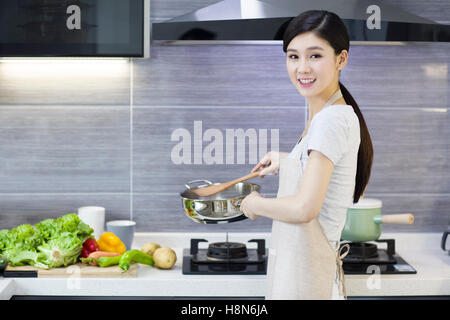 Felice giovane donna cinese per la cottura in cucina Foto Stock