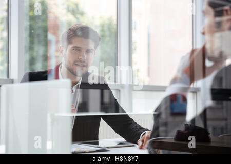 Due attraenti i giovani imprenditori seduto e parlando al meeting di lavoro in ufficio Foto Stock