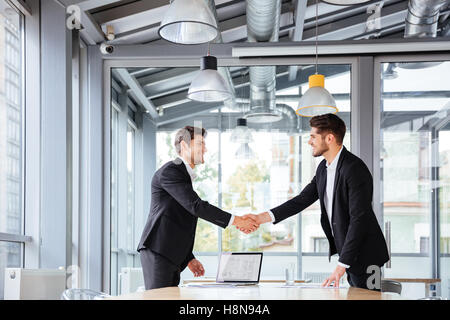 Due felice successo i giovani imprenditori in piedi e agitando le mani sul business meeting Foto Stock