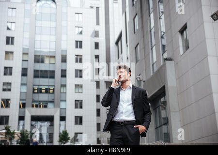 Sorridente giovane imprenditore parlando al telefono cellulare nella città Foto Stock