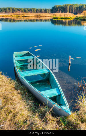 Autumn Fall mattina paesaggio del lago o fiume con un vecchio blu piccola barca a remi barca da pesca su di esso. Foto Stock