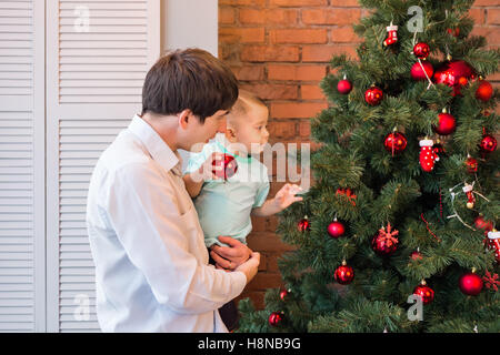 Padre e figlio sono decorare l'albero di Natale Foto Stock