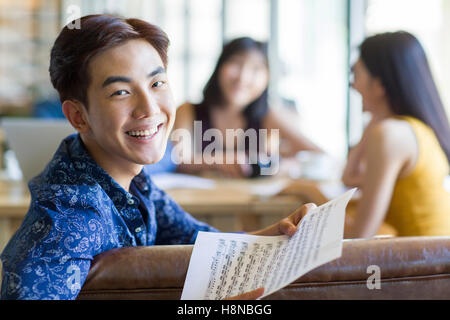 Giovane uomo cinese tenendo in mano un pezzo di musica del foglio Foto Stock