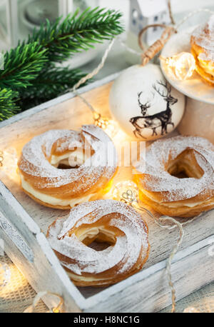 Soffio di crema anelli (bignè) bianco su sfondo di Natale Foto Stock