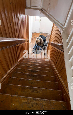 Giovane donna in sedia a rotelle al fondo delle scale Foto Stock