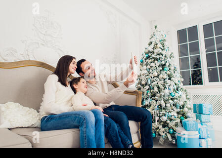 Natale, vacanze, la tecnologia e le persone - Concetto di famiglia sorridente con tablet pc tenendo selfie a casa Foto Stock