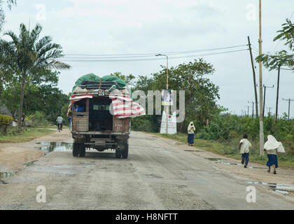 Un dala dala su una strada a Zanzibar con scolari camminando accanto alla strada Foto Stock