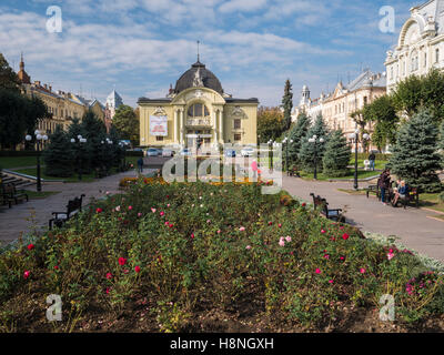 Splendidi edifici che circondano la piazza Teatralina in Chernivtsi, Ucraina. Le rose sono in fiore nel centro Foto Stock