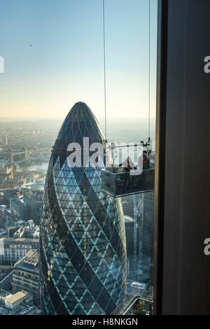 Lavoratori sospesi in un cavo collegato culla ispezionare le finestre superiori della Heron Tower con il famoso 'gherkin'. Foto Stock