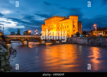 Sarajevo City Hall e Šeher-Ćehaja ponte sul fiume Miljacka, in Bosnia ed Erzegovina. Foto Stock