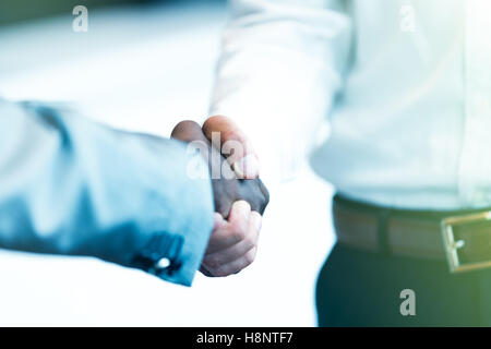 Stretta di mano tra africani e di un uomo caucasico Foto Stock