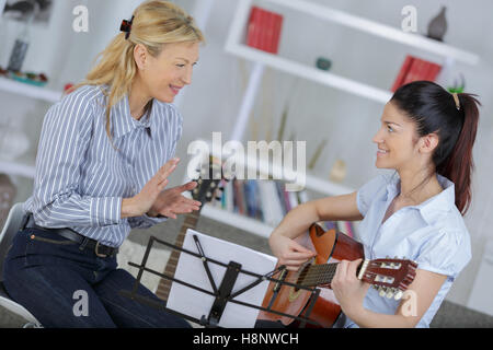 Signora insegnare ai giovani la donna come suonare la chitarra Foto Stock