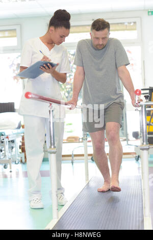 Paziente di sesso maschile in piedi con un fisioterapista Foto Stock