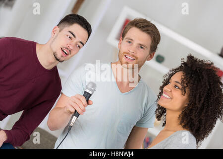 Gruppo di amici avente divertente karaoke cantare a casa Foto Stock