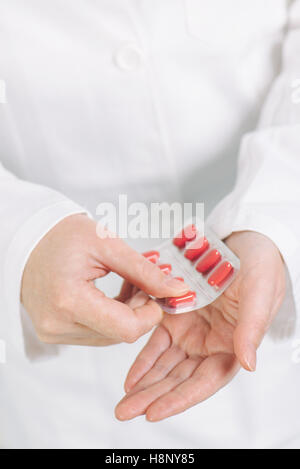 Medico donna offrendo le compresse di colore rosso per il paziente, la sanità e la farmacia concetto, il fuoco selettivo Foto Stock