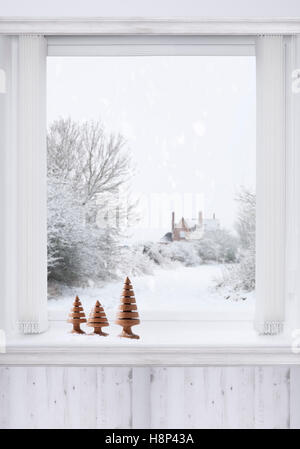 Finestra di inverno con girata in legno di alberi di Natale seduto sulla mensola Foto Stock