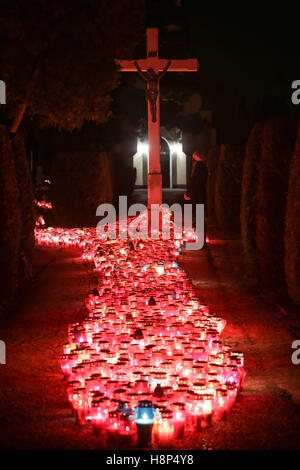 Una vista notturna di una donna che prega davanti alla croce al cimitero di Velika Gorica, Croazia. Foto Stock