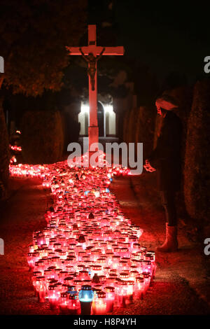 Una vista notturna di una donna che prega davanti alla croce al cimitero di Velika Gorica, Croazia. Foto Stock