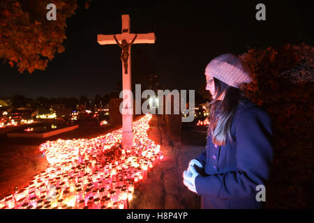 Una vista notturna di una donna che prega davanti alla croce al cimitero di Velika Gorica, Croazia. Foto Stock