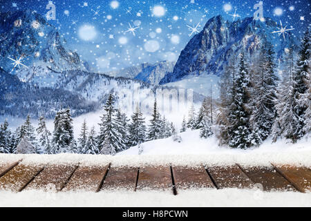 Natale Natale sfondo con legno doghe nevoso davanti a foreste di montagna paesaggio notte blu cielo con le stelle e il simbolo del fiocco di neve Foto Stock