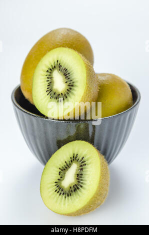 Kiwi e metà con ciotola nero su sfondo bianco Foto Stock