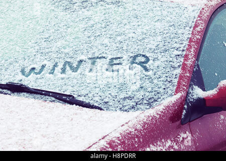 Inverno di parola scritta su di un parabrezza di automobile coperta di neve fresca Foto Stock