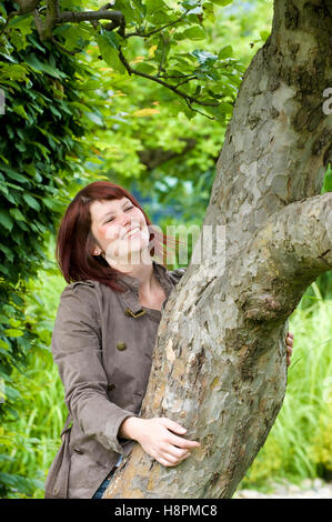Donna Felice, 25 +, abbracciando un albero Foto Stock