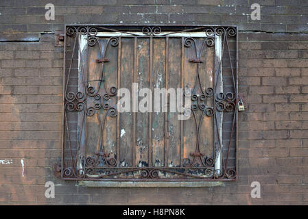 Bloccato le barre di ferro battuto rosso finestra rusty grill muro di mattoni Foto Stock