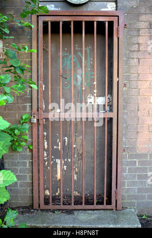 Le barre di blocco porta gate rosso griglia arrugginito un muro di mattoni Foto Stock