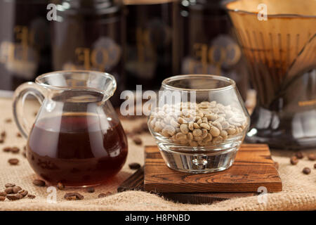 Pot del caffè appena fatto con il vetro del chicco di caffè verde Foto Stock