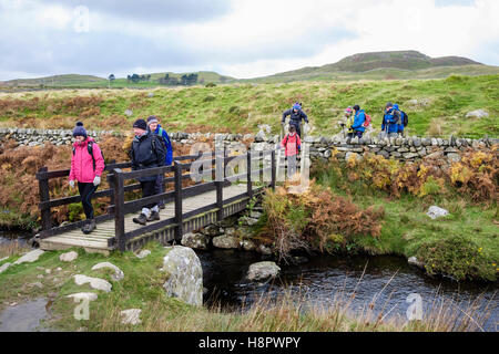 Gruppo di escursionisti a piedi attraverso una passerella sul Afon Gyrach fiume sul Galles del Nord il percorso nelle colline vicino a Ross on Wye Conwy Wales UK Gran Bretagna Foto Stock