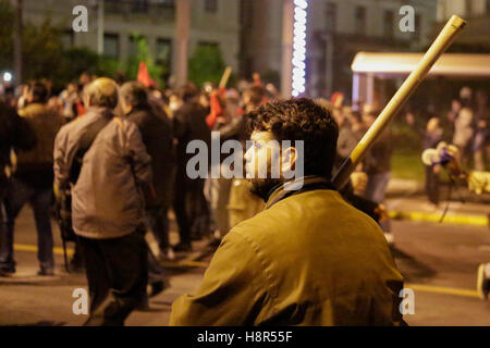 Atene, Grecia. Il 15 novembre 2016. Un manifestante attende con una bandiera, di attaccare la polizia. Migliaia di manifestanti hanno seguito la chiamata dall'Unione Comunista PAME e gruppi anarchici a venire per le strade di Atene e di protesta contro la visita del Presidente degli Stati Uniti Barack Obama. La protesta si è conclusa con scontri tra dimostranti e polizia. Manifestanti gettare bombe molotov contro i poliziotti che hanno risposto con gas lacrimogeni. Credito: Michael Debets/Alamy Live News Foto Stock