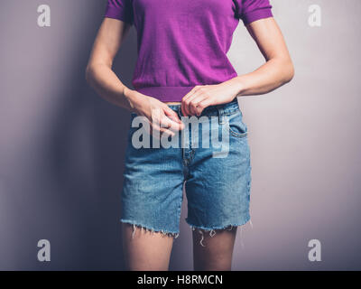 Una giovane donna è la chiusura della cerniera lampo sul suo pantaloncini denim Foto Stock
