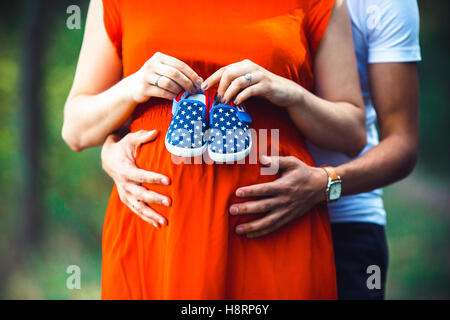 Moglie incinta e suo marito azienda scarpe per bambini Foto Stock