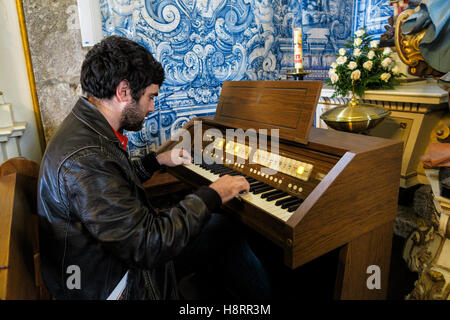 Giovane uomo che gioca organo di legno durante il servizio della chiesa all'interno del Santuário de Nossa Senhora do Pilar, Povoa de Lanhoso, Portogallo, Europa Foto Stock