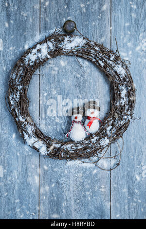 Inverno ghirlanda appesa su rustiche porta in legno con decorazione pupazzo di neve Foto Stock