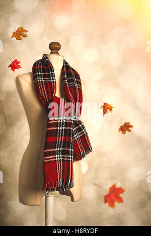 Inverno tartan plaid sciarpa flottante con foglie di autunno Foto Stock