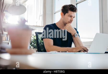 Bel giovane utilizzando laptop. Imprenditore navigare in internet sul suo computer portatile. Foto Stock